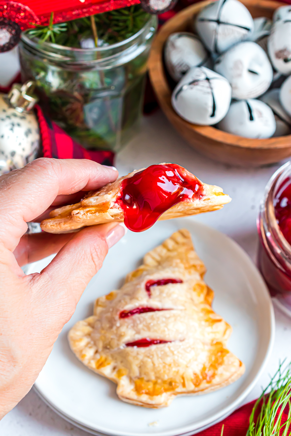 A Christmas Tree Cherry Hand Pie with a bite taken out of it and cherry pie filling dripping from the opening in the crust.