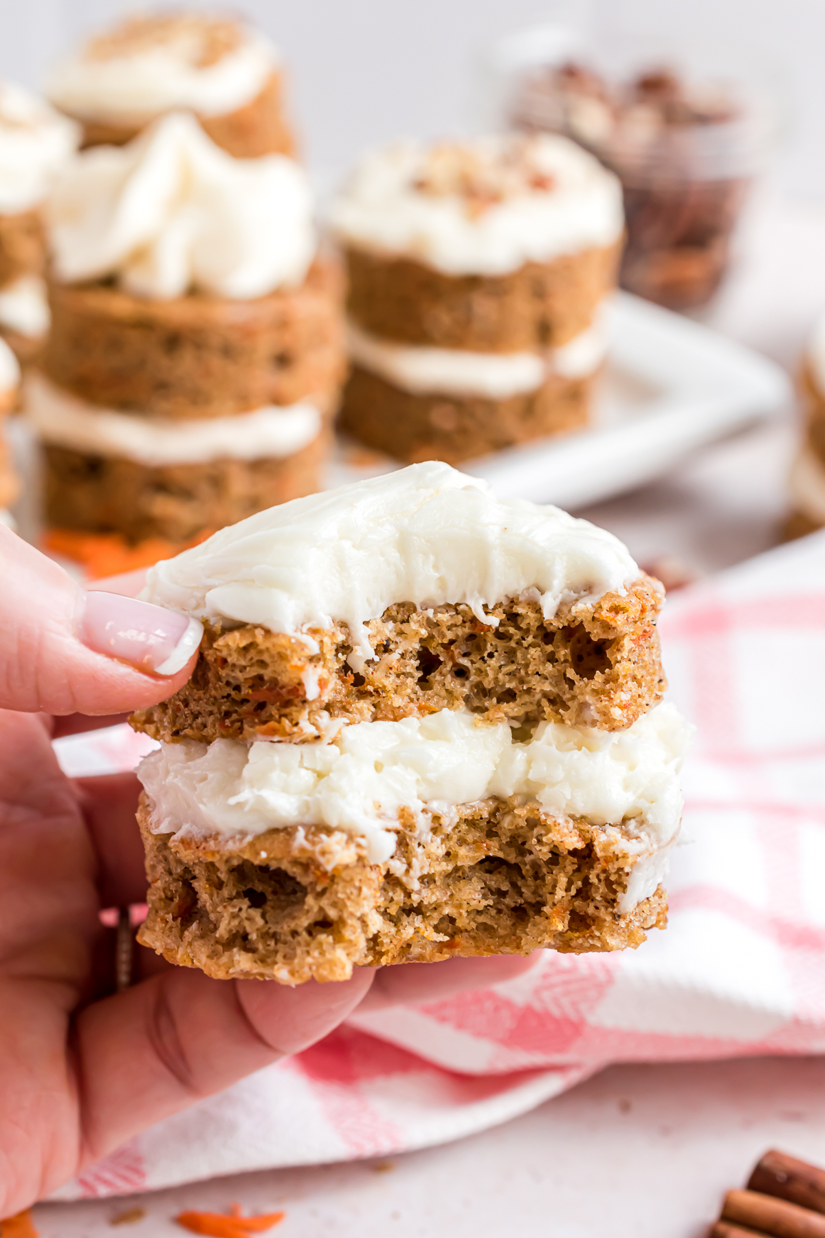 A mini carrot cake with a bite taken out of it showing the texture of the cakes and the icing in between the layers.