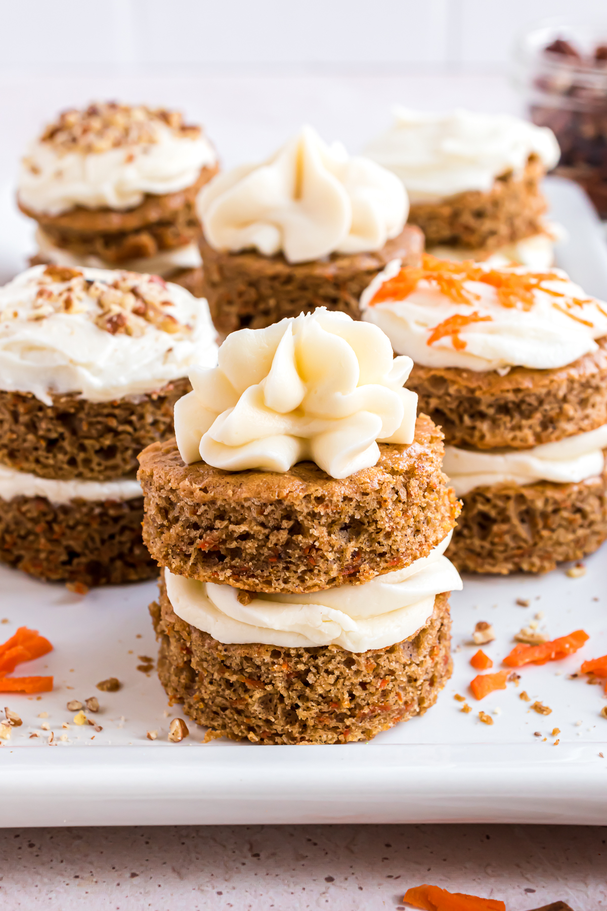 An photo showing a group of double-layered mini carrot cakes with piped frosting on top.