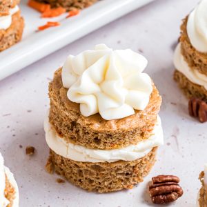 A double layered mini carrot cake with a dollop of cream cheese frosting piped on top