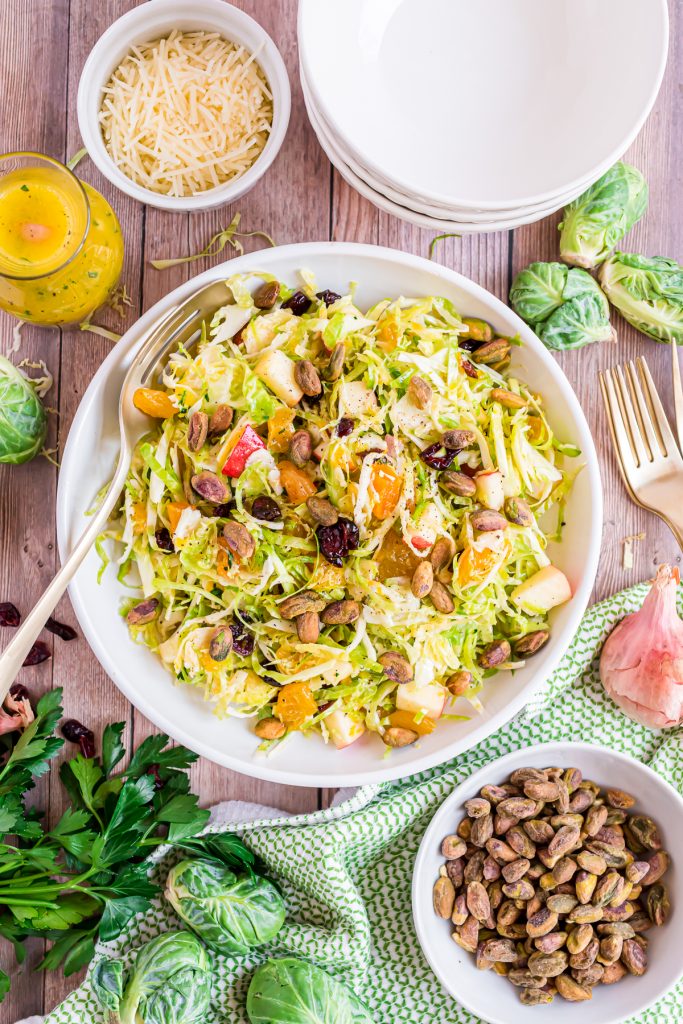 Large bowl filled with Brussels Sprout Salad topped with dried cranberries and pistachios.