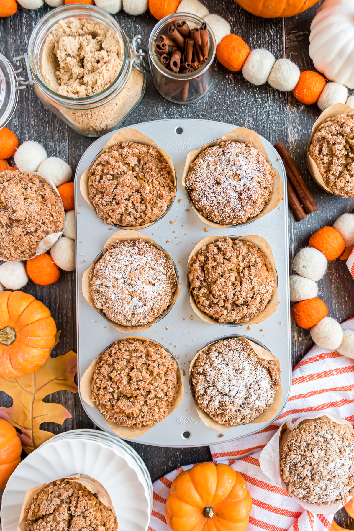 6 Jumbo Panera Bread Pumpkin Muffins in a muffin tin. Some topped with streusel and some topped with powdered sugar.