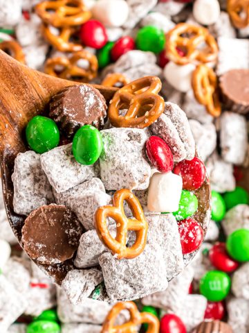 A large cookie sheet filled with reindeer chex mix and a large spoon digging into the mixture.