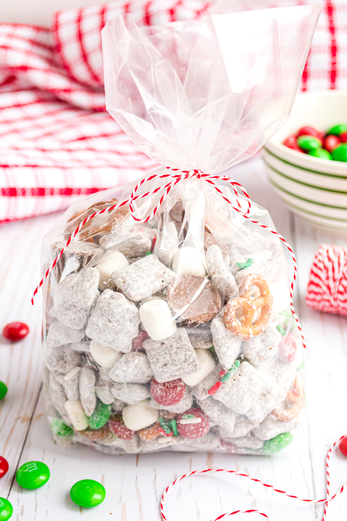 Reindeer Chex mix in a cellophane bag with red and white baker's twine tied in a bow.