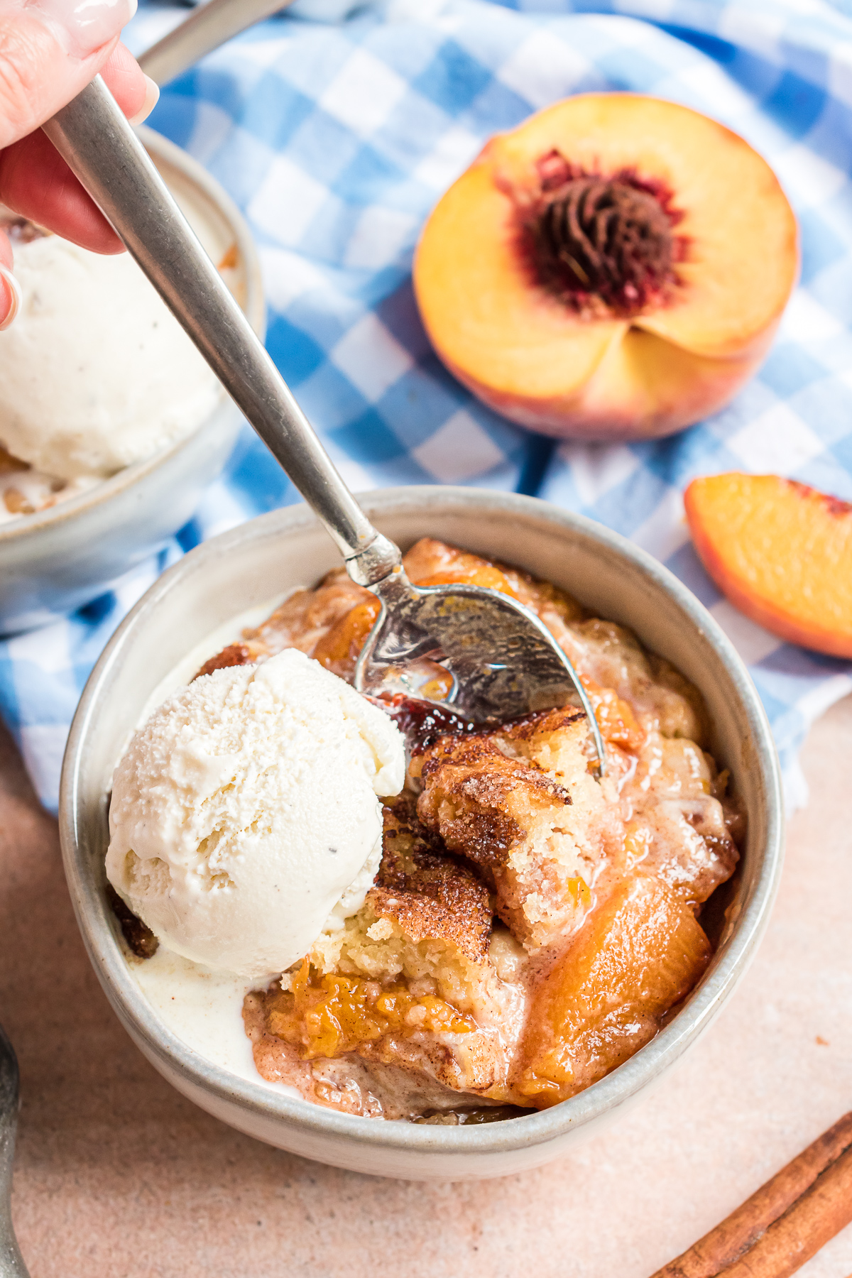 A bowl of peach cobbler with a large scoop of vanilla ice cream on top.