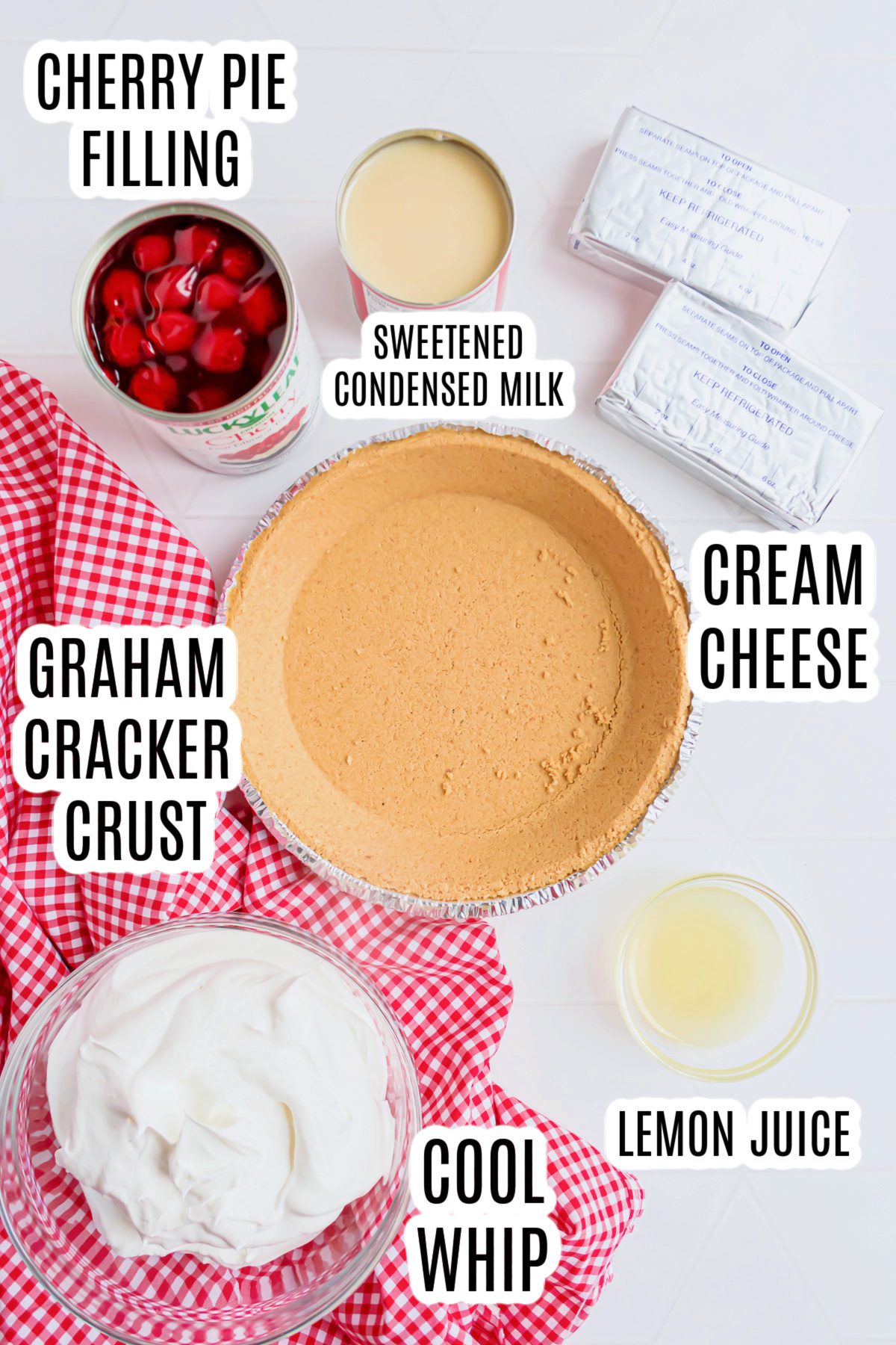 All the ingredients that are needed to make the no bake cherry pie with graham cracker crust, including a pre-made graham cracker crust, cream cheese, sweetened condensed milk, cherry pie filling, lemon juice, and cool whip.