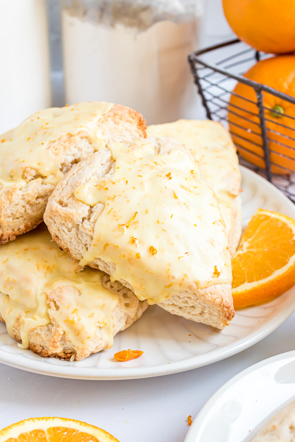 A pile of scones on a white round serving plate with orange slices placed around them.