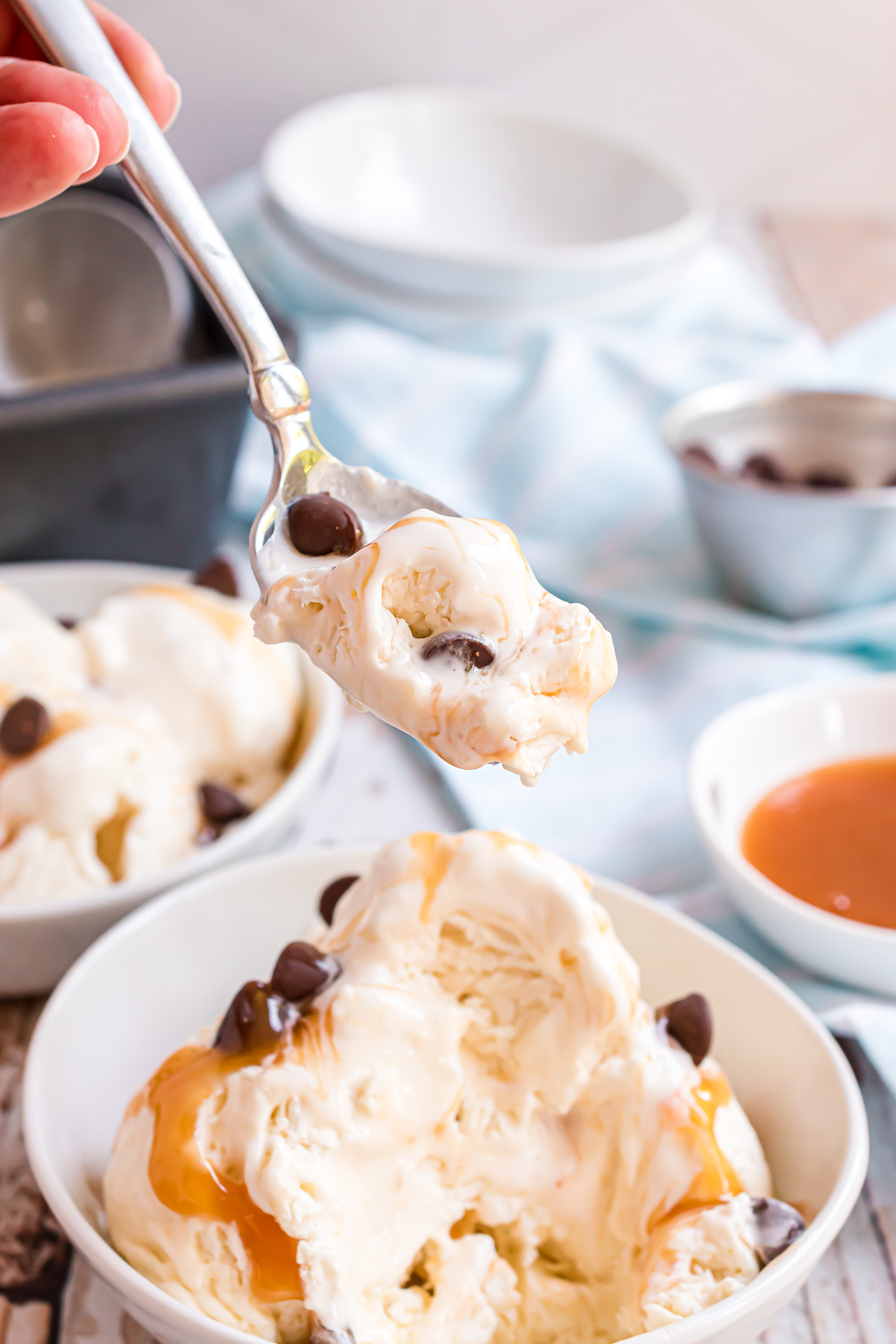 A spoonful of no churn vanilla ice cream ready to be eaten with caramel sauce and chocolate chips peeking out from the mixture.