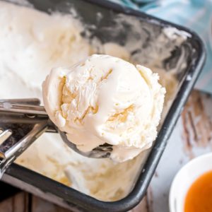 A loaf pan with no-churn vanilla ice cream in it and a large scoop getting a scoop of it.