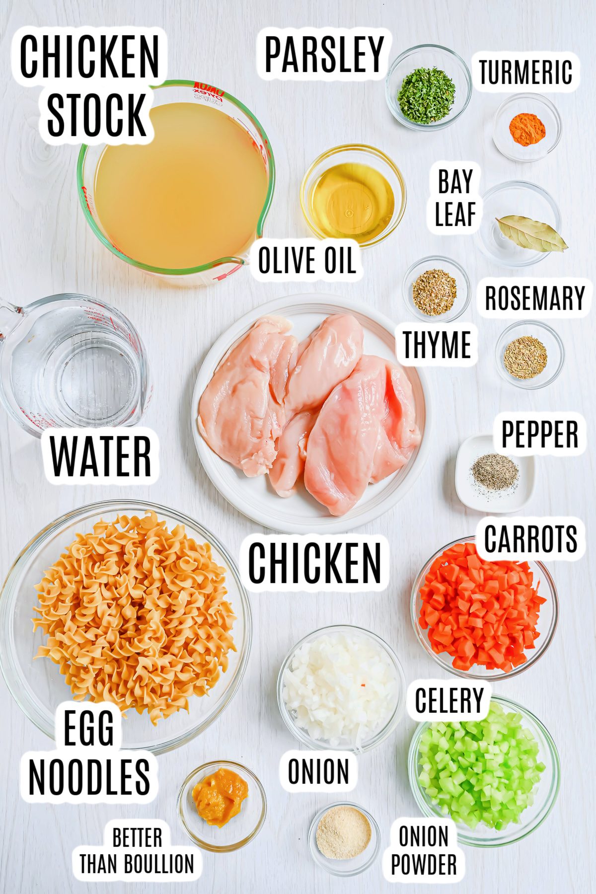 All the ingredients needed to make the Panera Chicken Noodle Soup (Copycat Recipe) including: chicken stock, parsley, turmeric, a bay leaf, olive oil, rosmemary, thyme, black pepper, carrots, chicken, egg noodles, onion, celery, onion powder, Better Than Boullion, and water.