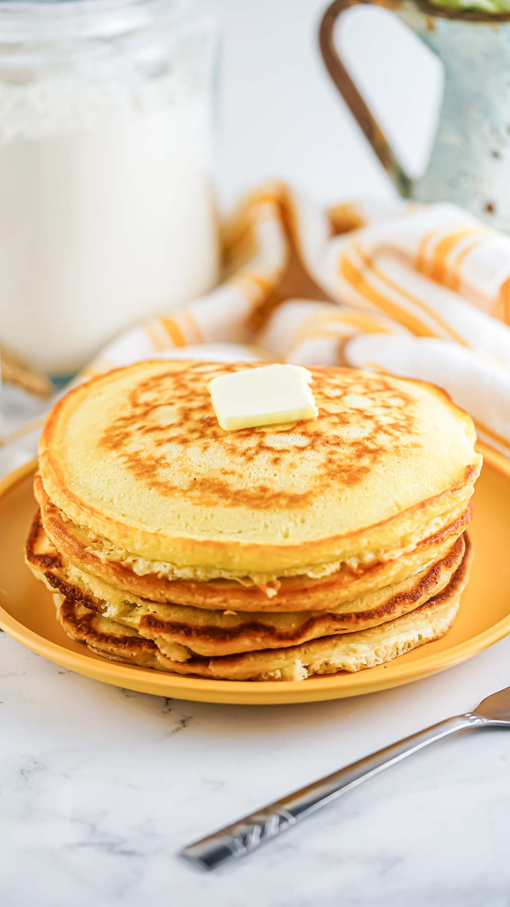 A stack of golden brown pancakes made by using the homemade bulk pancake mix recipe.