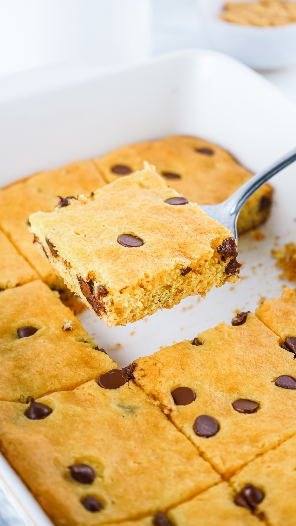 A pan of Cake Mix Cookie Bars with a bar being lifted out of the pan on a serving spatula.
