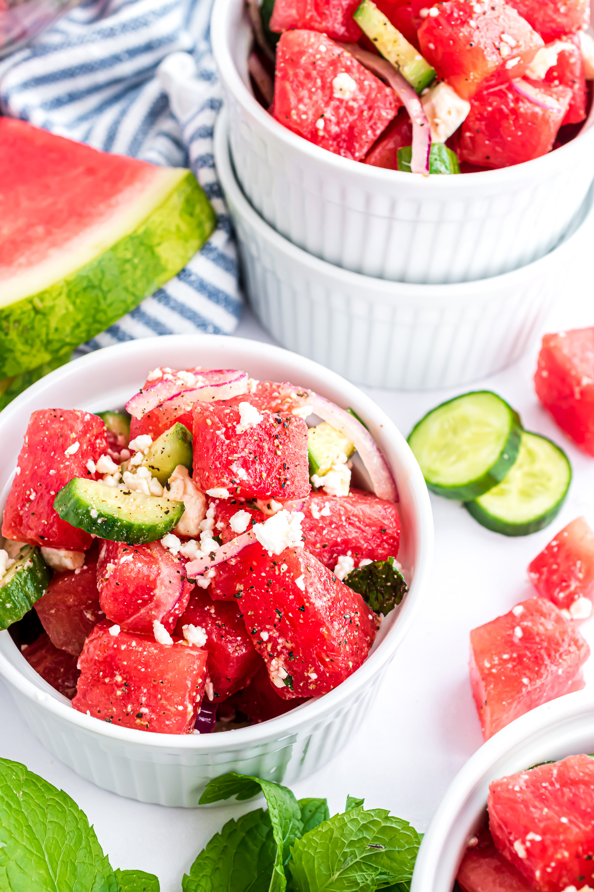A small bowl of watermelon salad with goat cheese, red onions and cucmber slices.