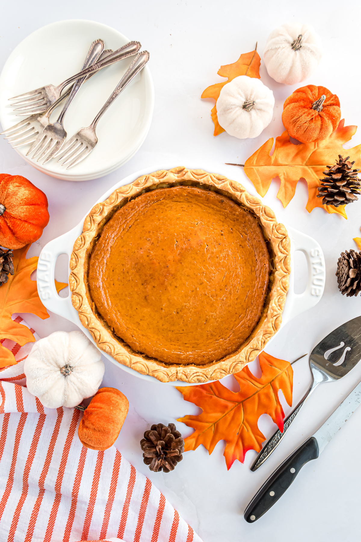 A baked pumpkin pie in a white ceramic pie plate with handles.