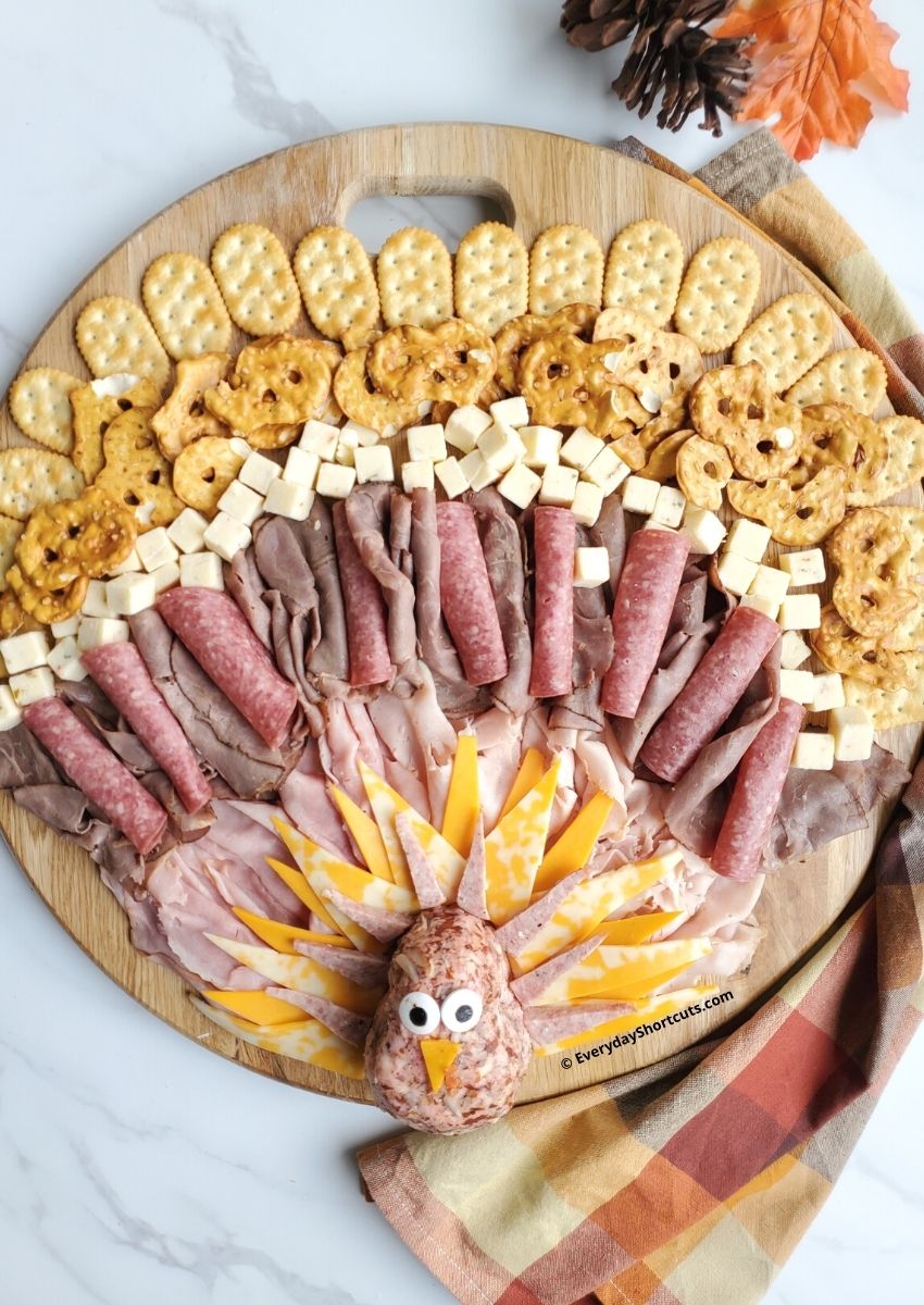 A board with a turkey made of cheese and meat.