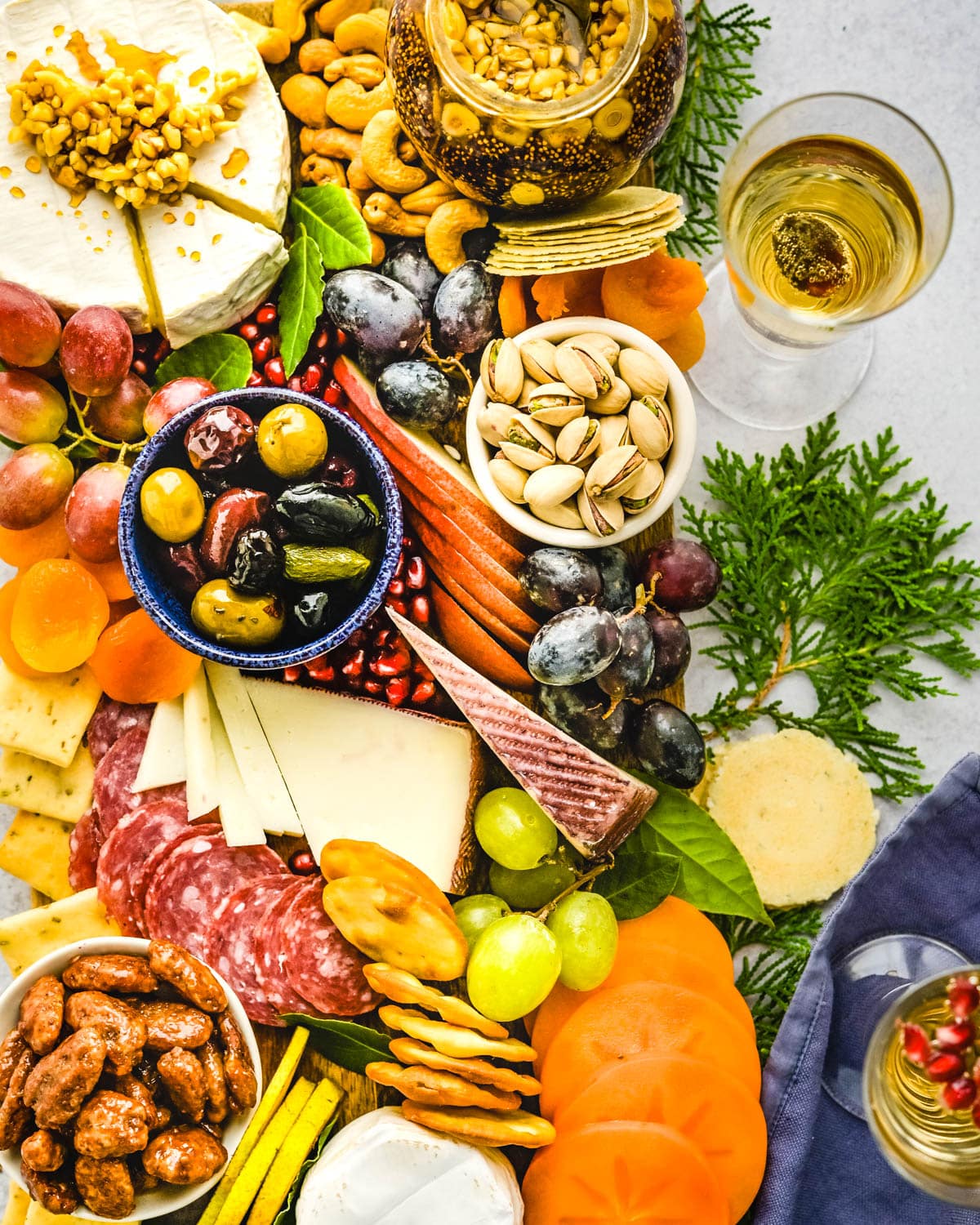 A charcuterie board that's perfect for the holiday season with pistachios, olives, grapes and dried fruits.