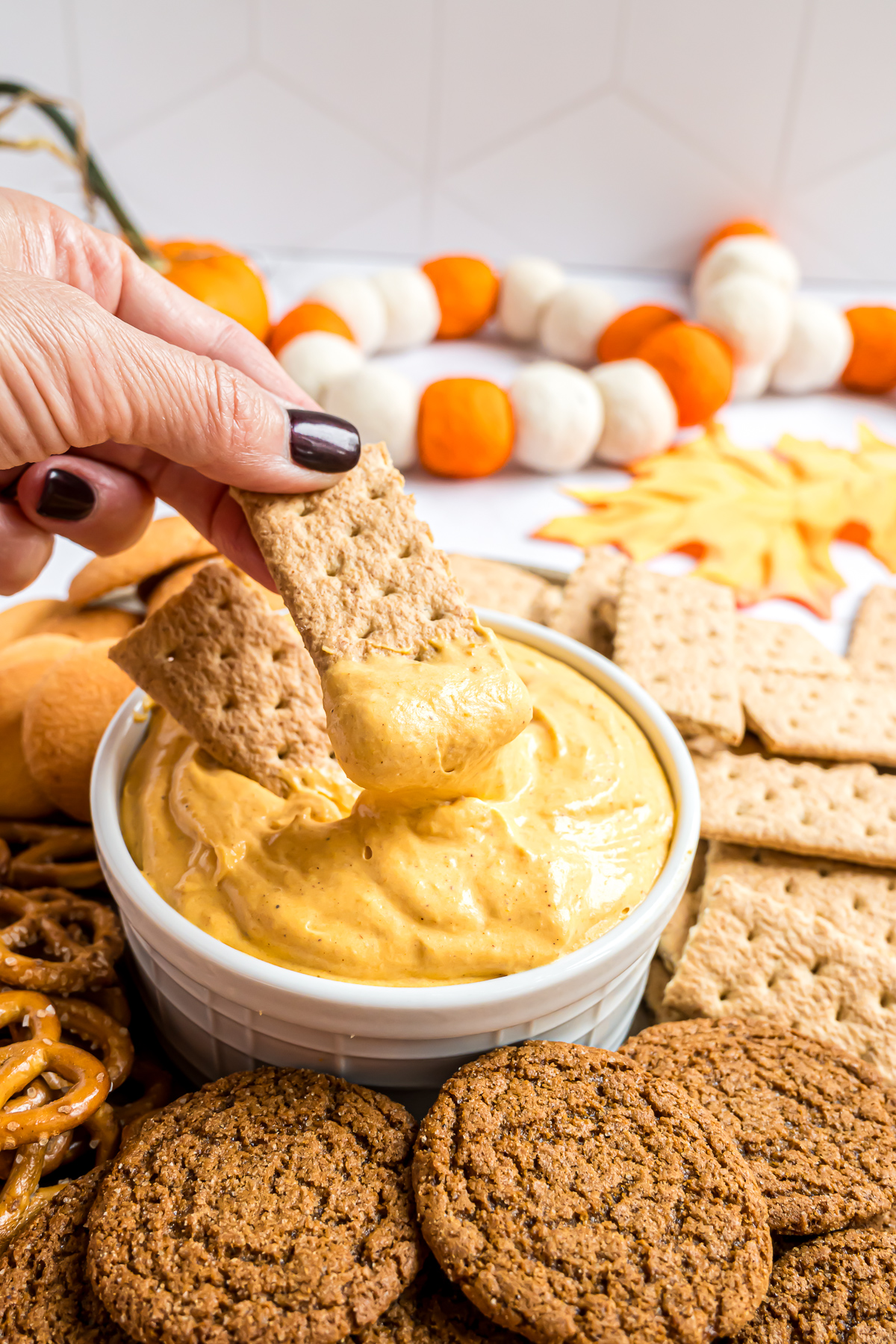 Graham crackers being dipped into the pumpkin fluff showing the creamy texture of the dip.