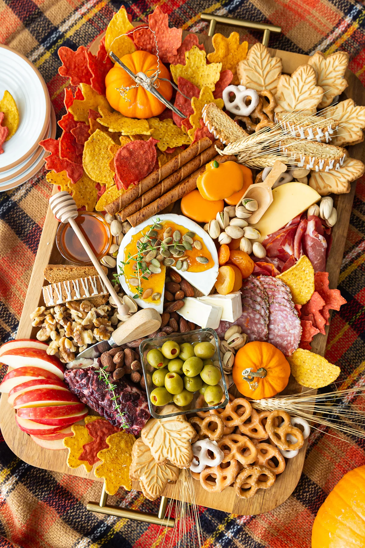A Thanksgiving charcuterie board with meats, cheese, nuts, pretzels, apple slices and mini pumpkins.