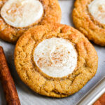 A pumpkin cookie covered with cinnamon sugar with a dollop of cheesecake in the center.