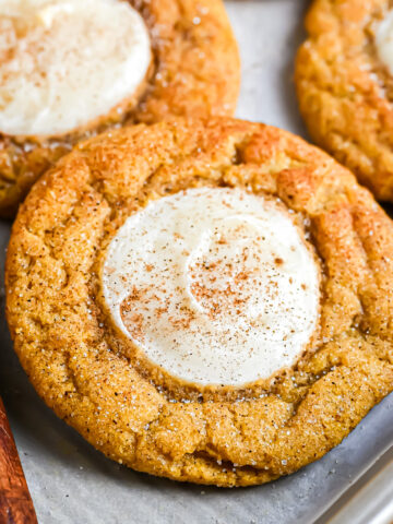 A pumpkin cookie covered with cinnamon sugar with a dollop of cheesecake in the center.