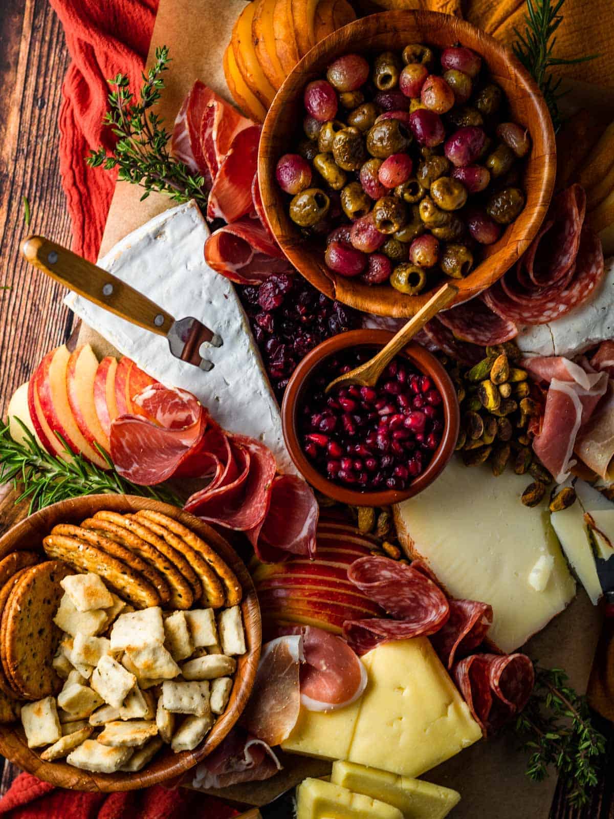 A rectangular meat and cheese board accented with olives and crackers.