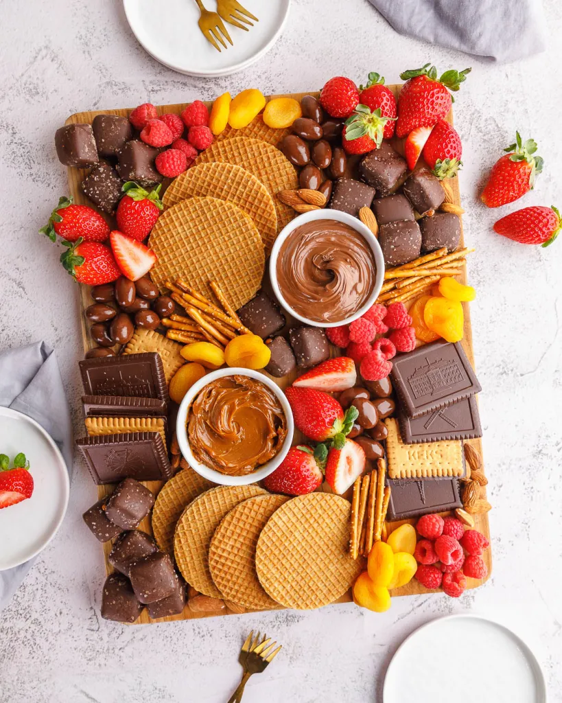 A dessert charcuterie board featuring chocolates and fruit.