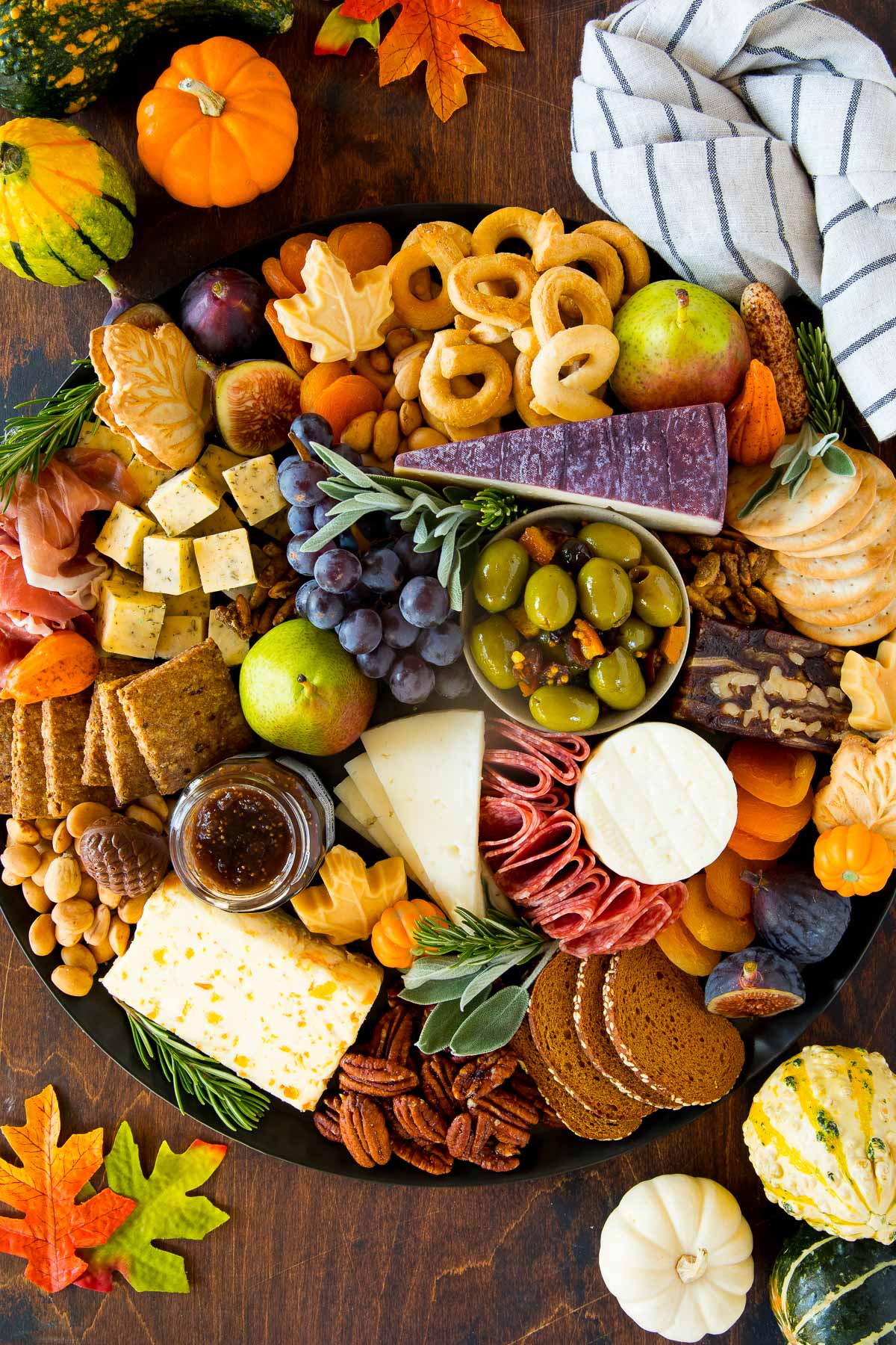 A Thanksgiving inspired board with nuts, fruit, olives and crackers.