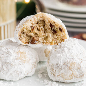 A classic snowball cookie broken in half showing the inside texture and chopped pecans.