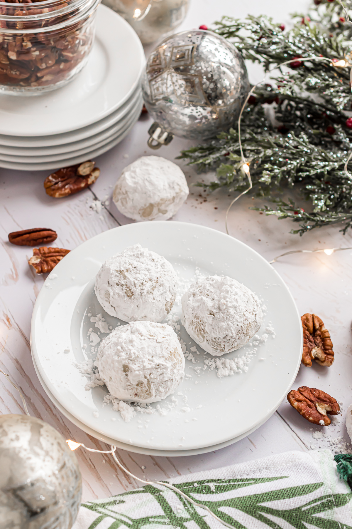 A white plate of 3 snowball cookies dusted with powdered sugar.