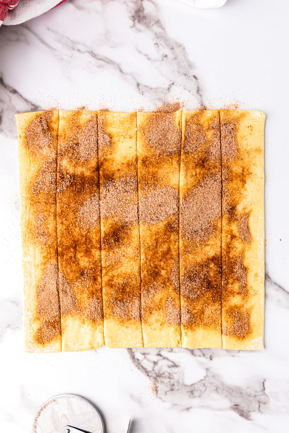 A sheet of puff pastry covered with cinnamon sugar and cut into 6 long strips.