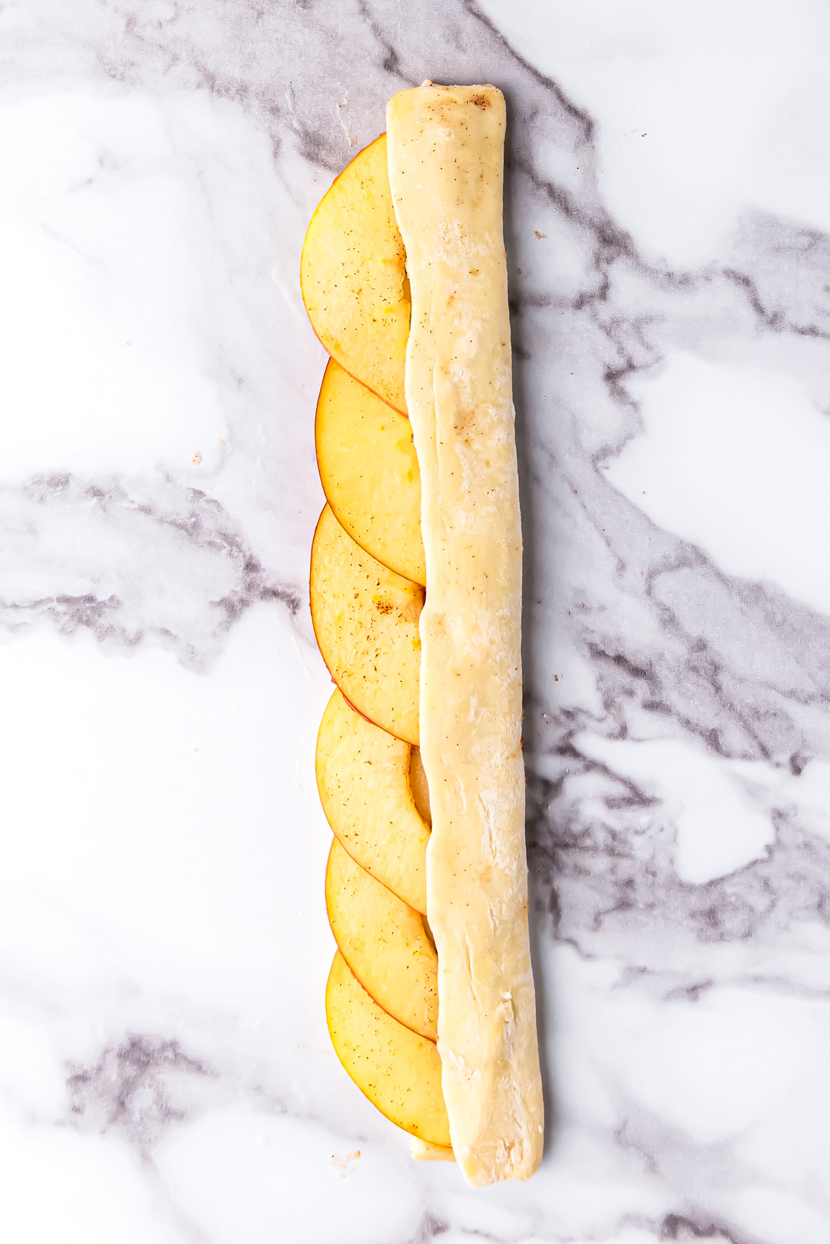 A strip of puff pastry folded around apple slices. 