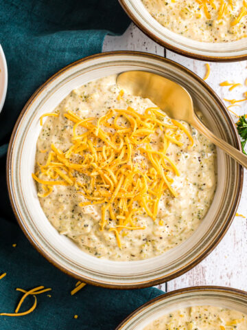 A bowl of Broccoli Cheese soup topped with shredded cheese.