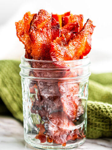 A glass mason jar filled with strips of candied maple bacon.