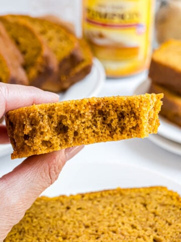 A piece of pumpkin bread with a bite taken out of it to expose the moist texture of the bread.