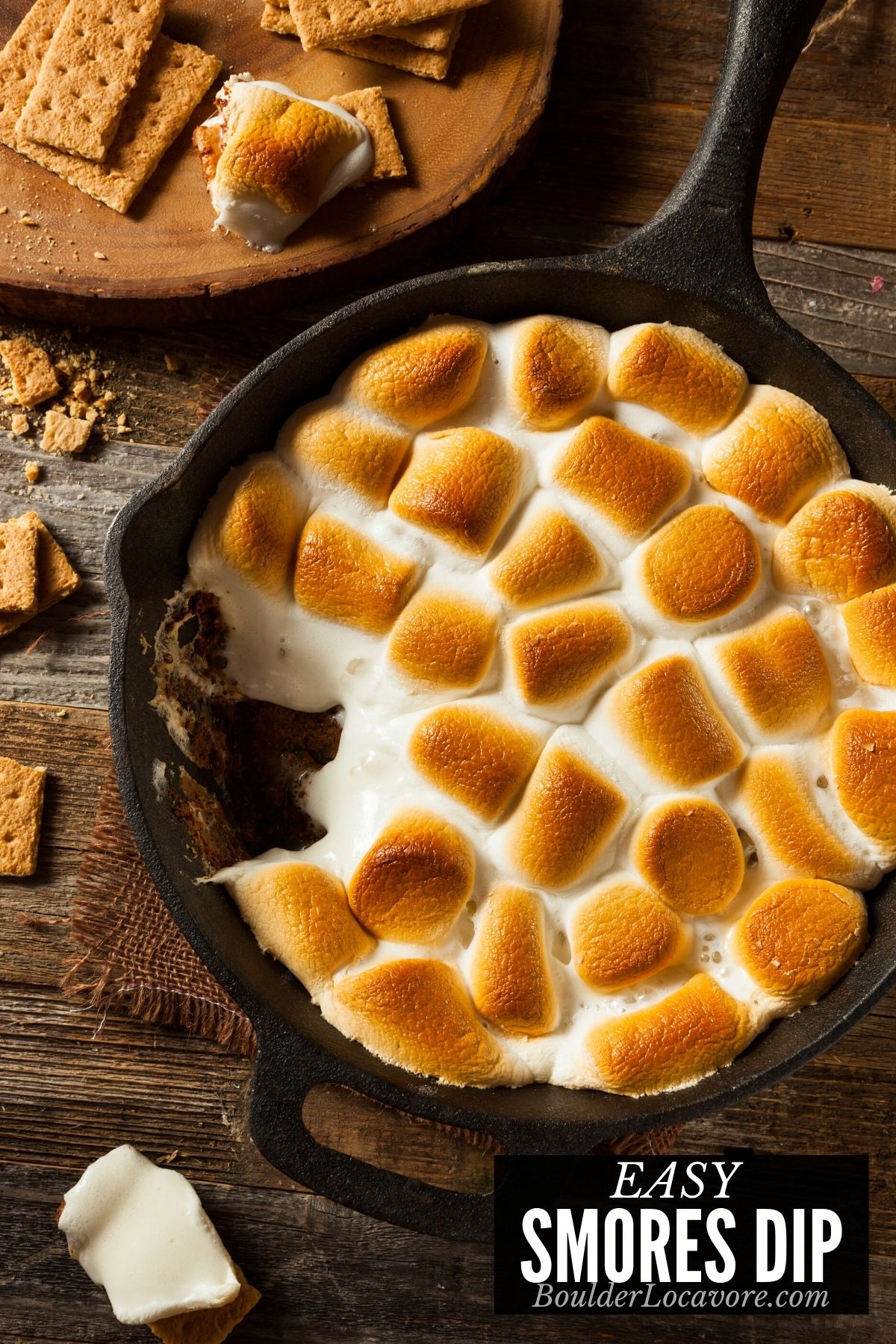 A cast iron skillet filled with S'mores Dip topped with toasted marshmallows.