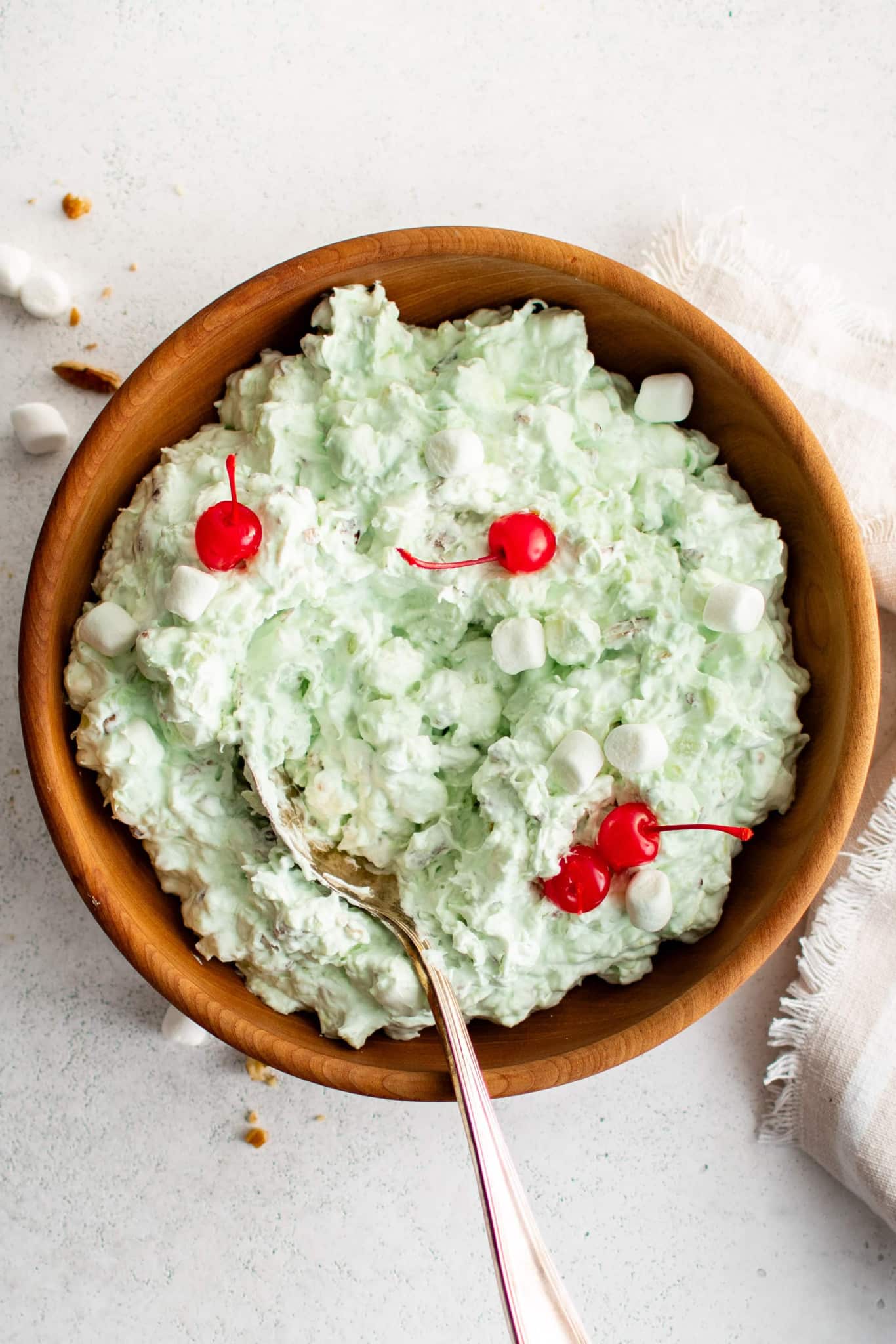 A bowl of Watergate Salad topped with cherries.