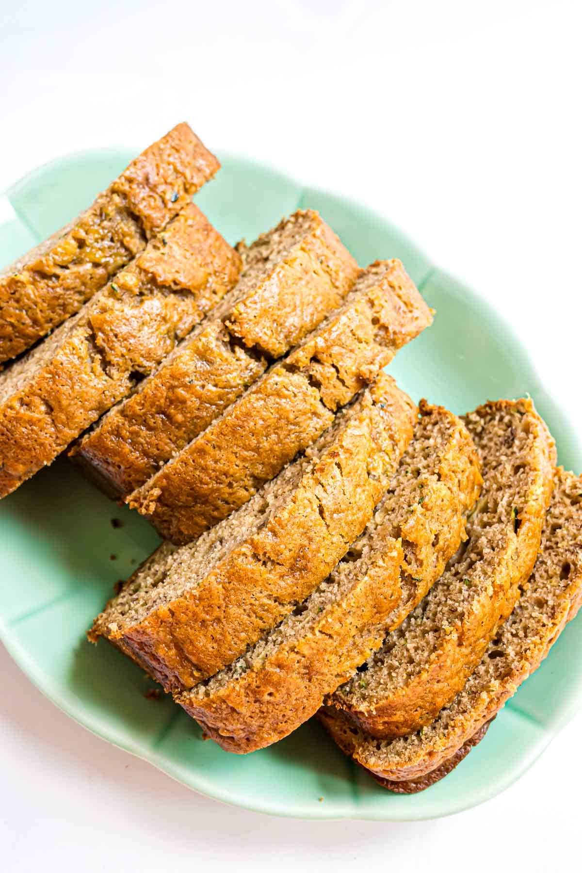 Sliced banana zucchini bread arranged on a light green plate against a white background.