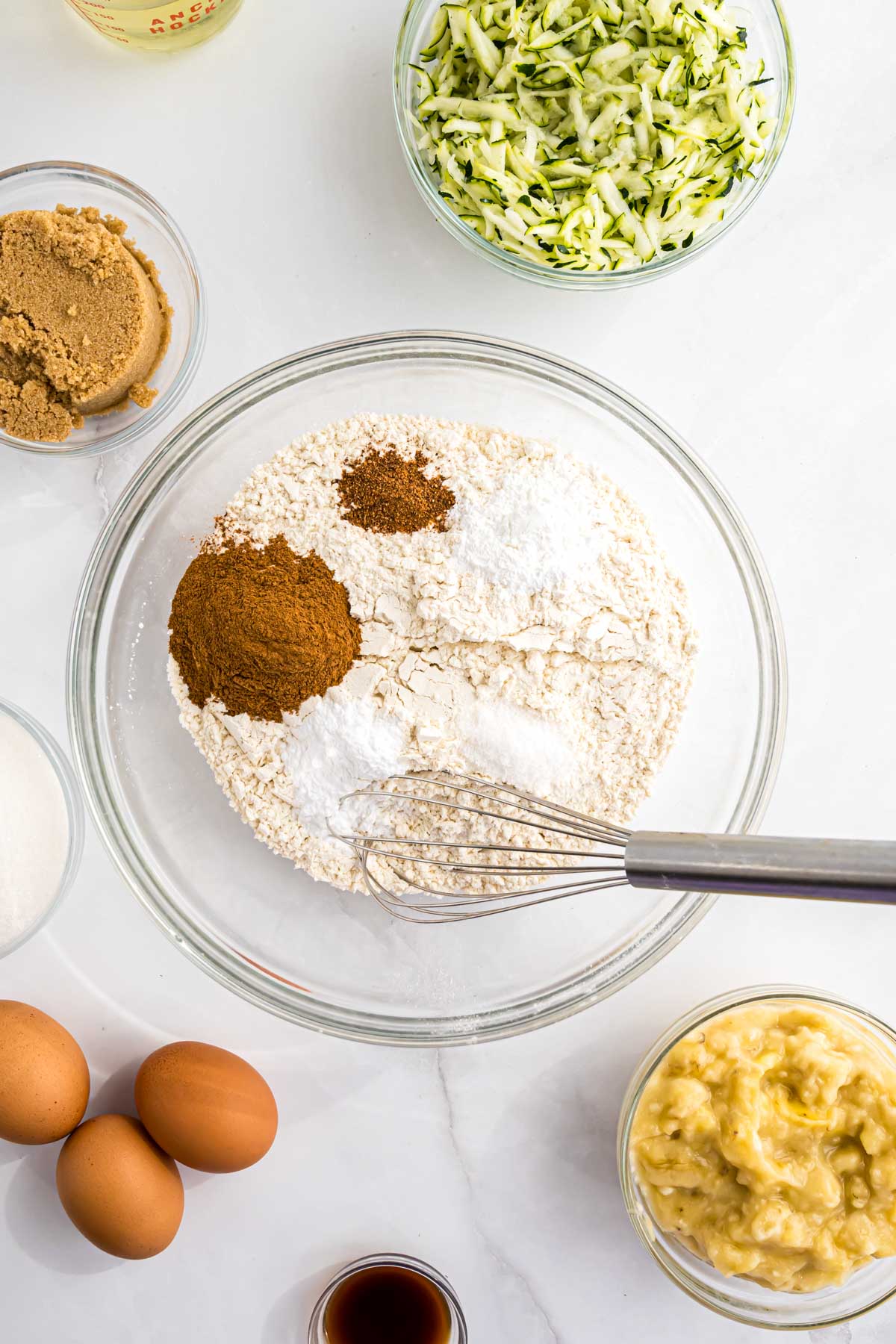 The dry ingredients needed to make the banana zucchini bread in a mixing bowl ready to be whisked together.