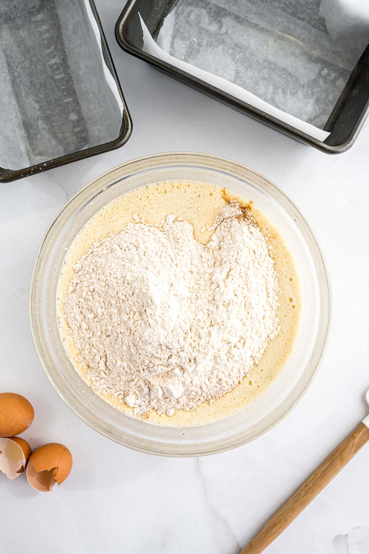The bread batter in a large mixing bowl with the dry ingredients being stirred in.