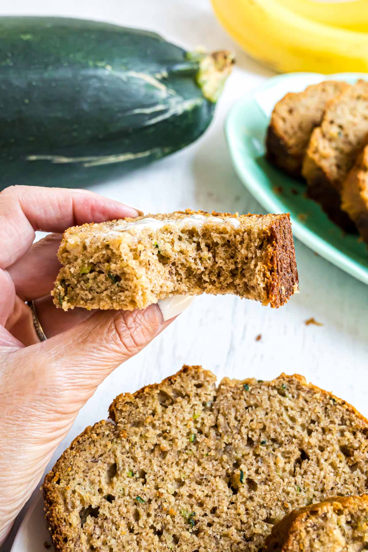 A slice of banana zucchini bread that has a bite taken out of it.