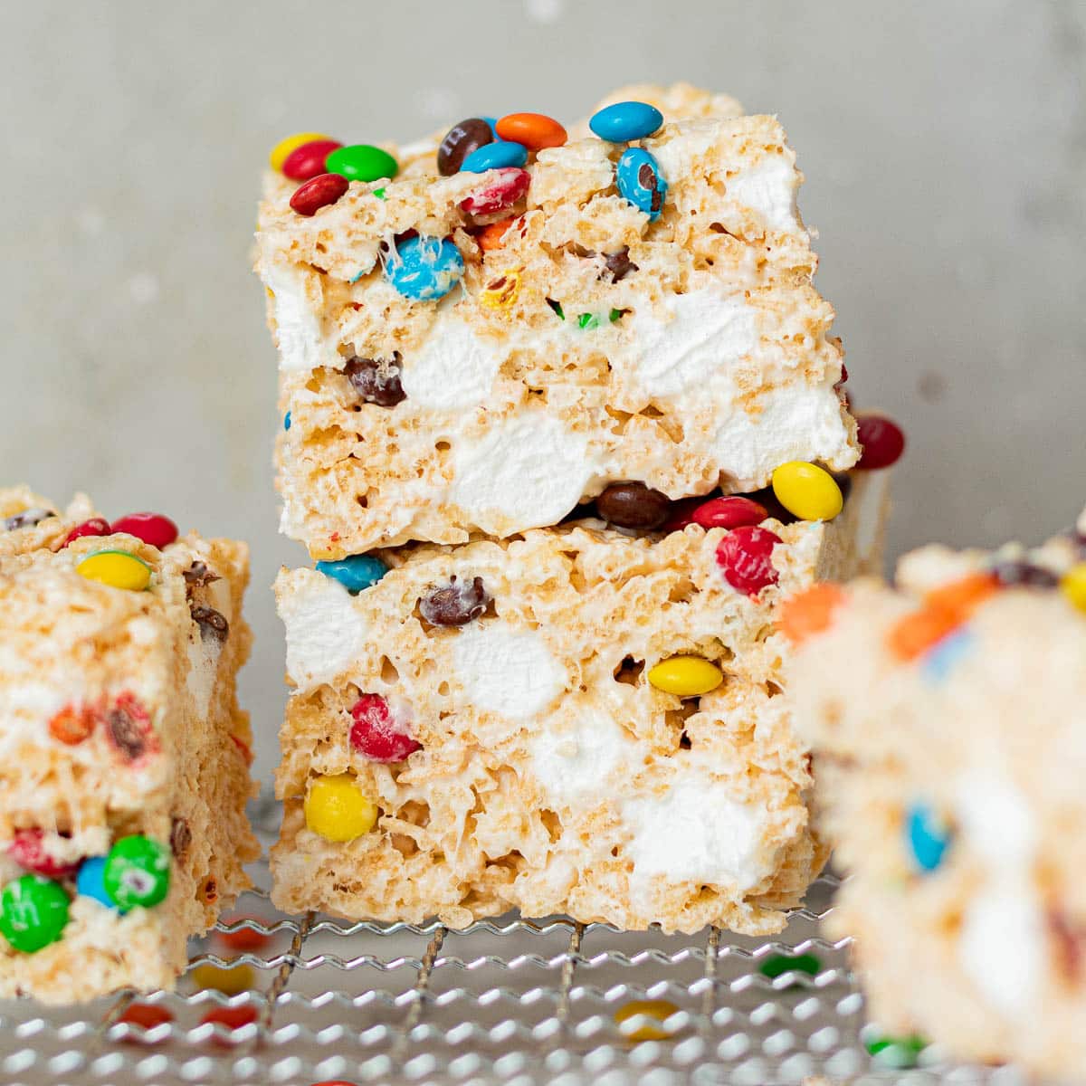M&M Rice Krispie Treats stacked on a cooling rack.