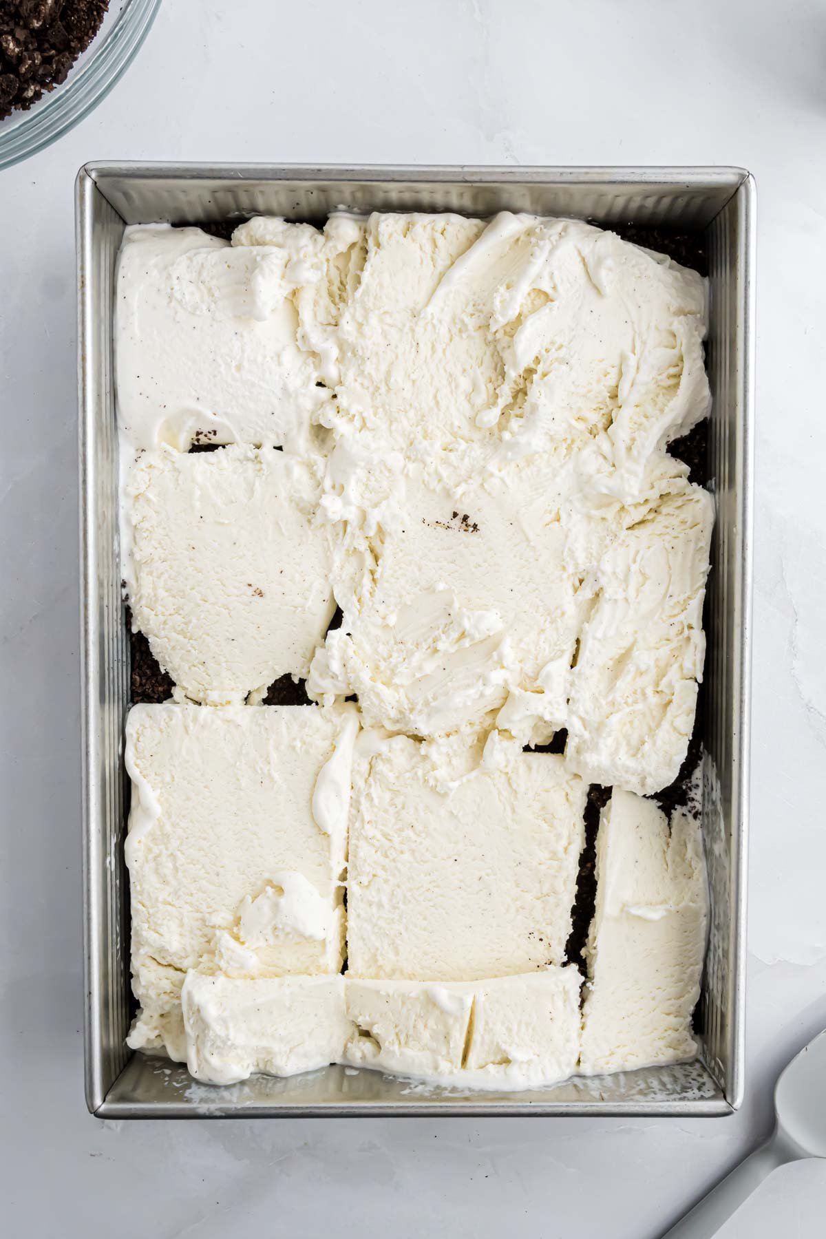 The ice cream dessert with slabs of vanilla ice cream layered evenly in the 9" x 13" pan.