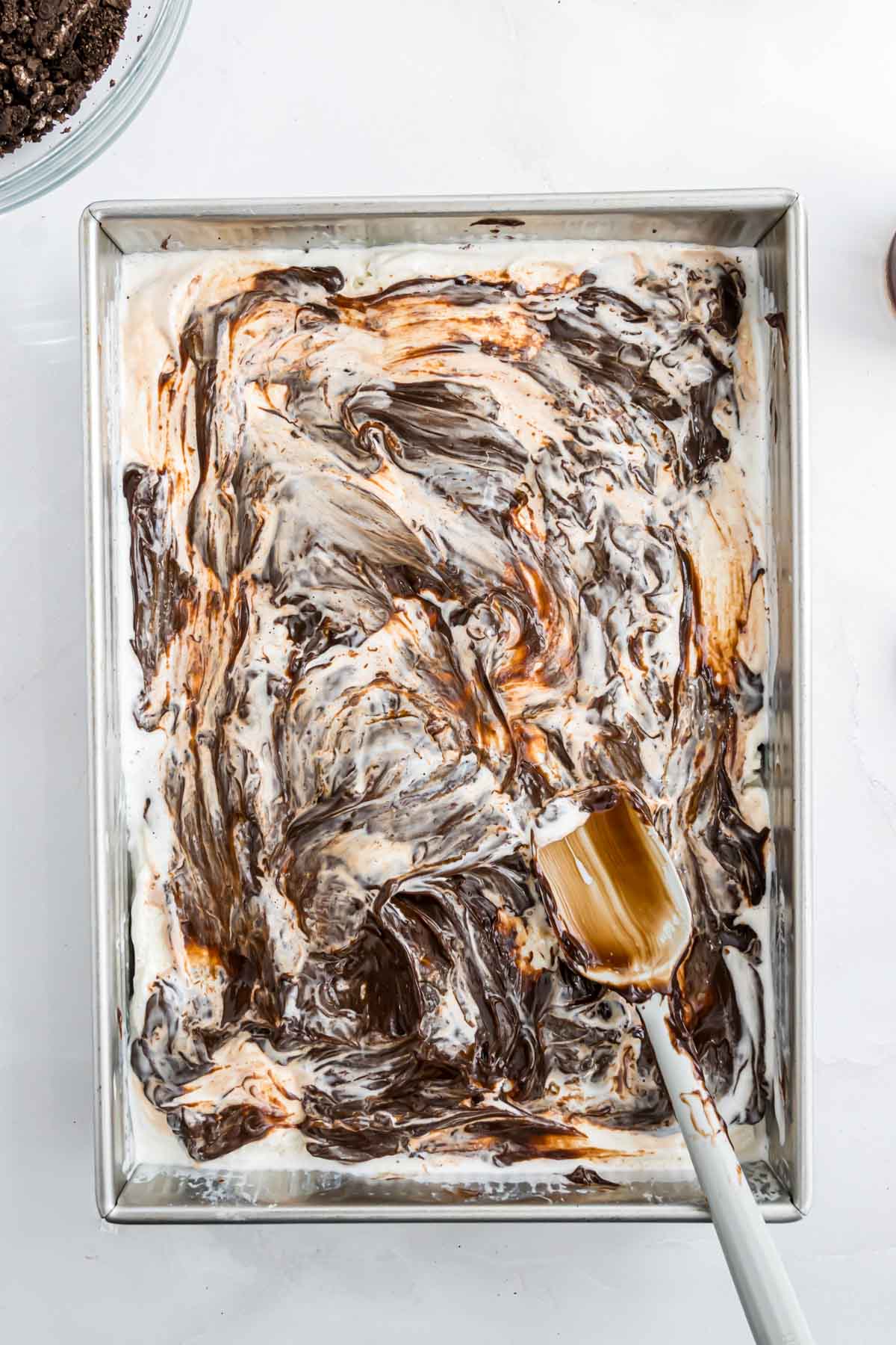 The ice cream dessert with dollops of hot fudge sauce spread into a layer.