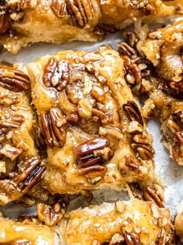 Pecan rolls with a gooey caramel topping on a baking sheet.