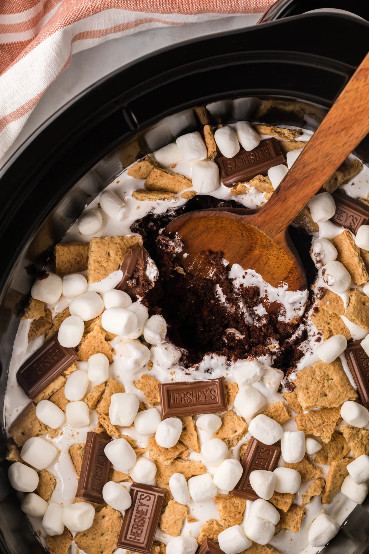 A chocolate cake topped with mini marshmallows, hershey's chocolate bars and graham cracker pieces in a slow cooker.