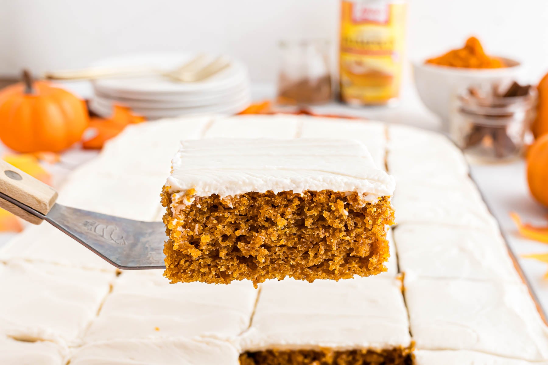 A pumpkin bar with cream cheese frosting on a spatula.
