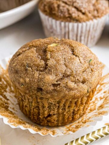 A Banana Zucchini Muffin with the muffin wrapper peeled away to reveal the inside texture of the muffin.