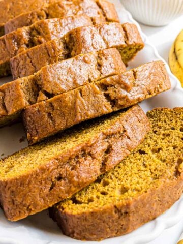 A loaf of Pumpkin Banana Bread on a cutting boards that has been cut into slices.