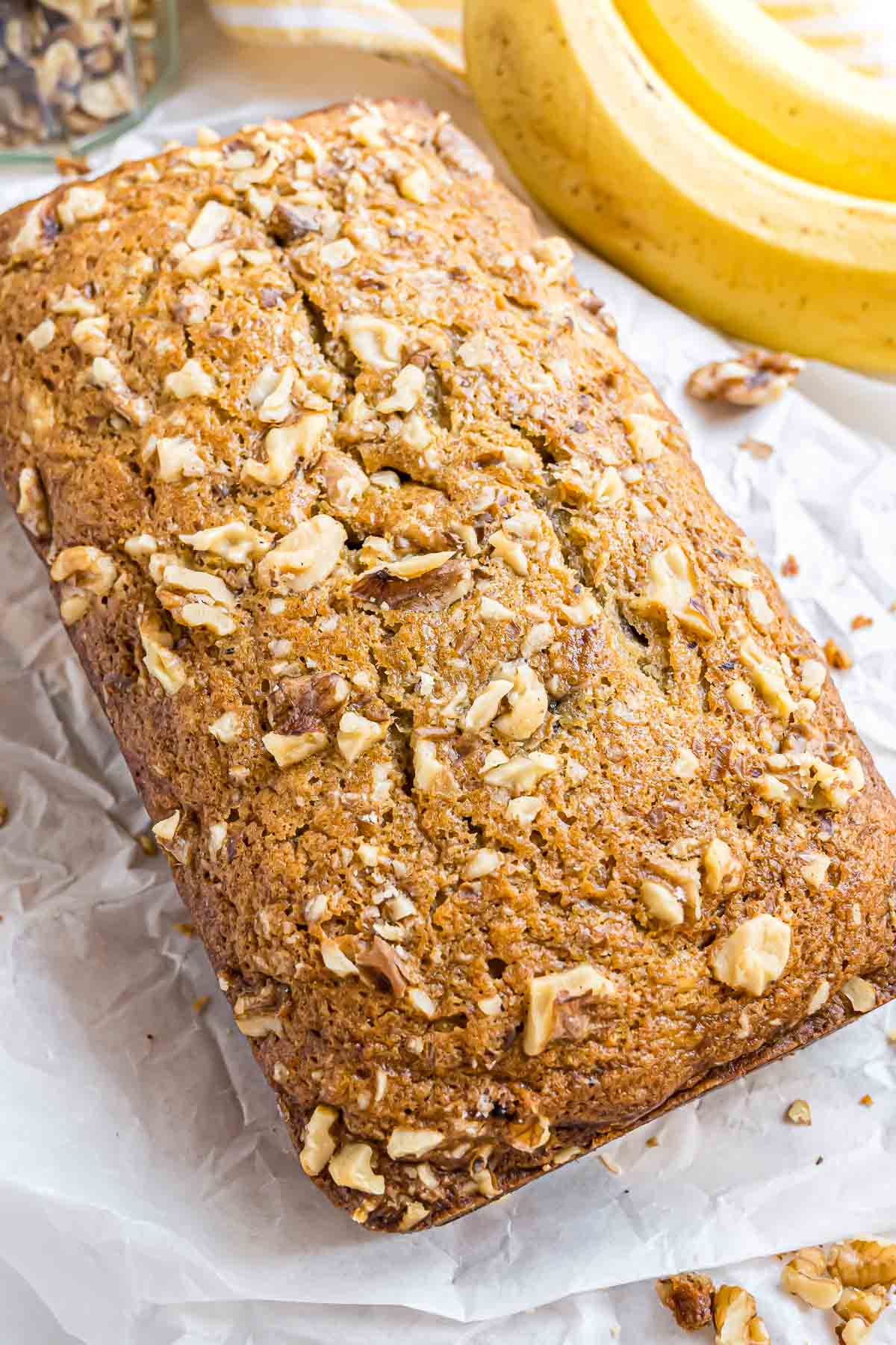 A loaf of freshly baked Banana Nut Bread on a piece of parchment paper.