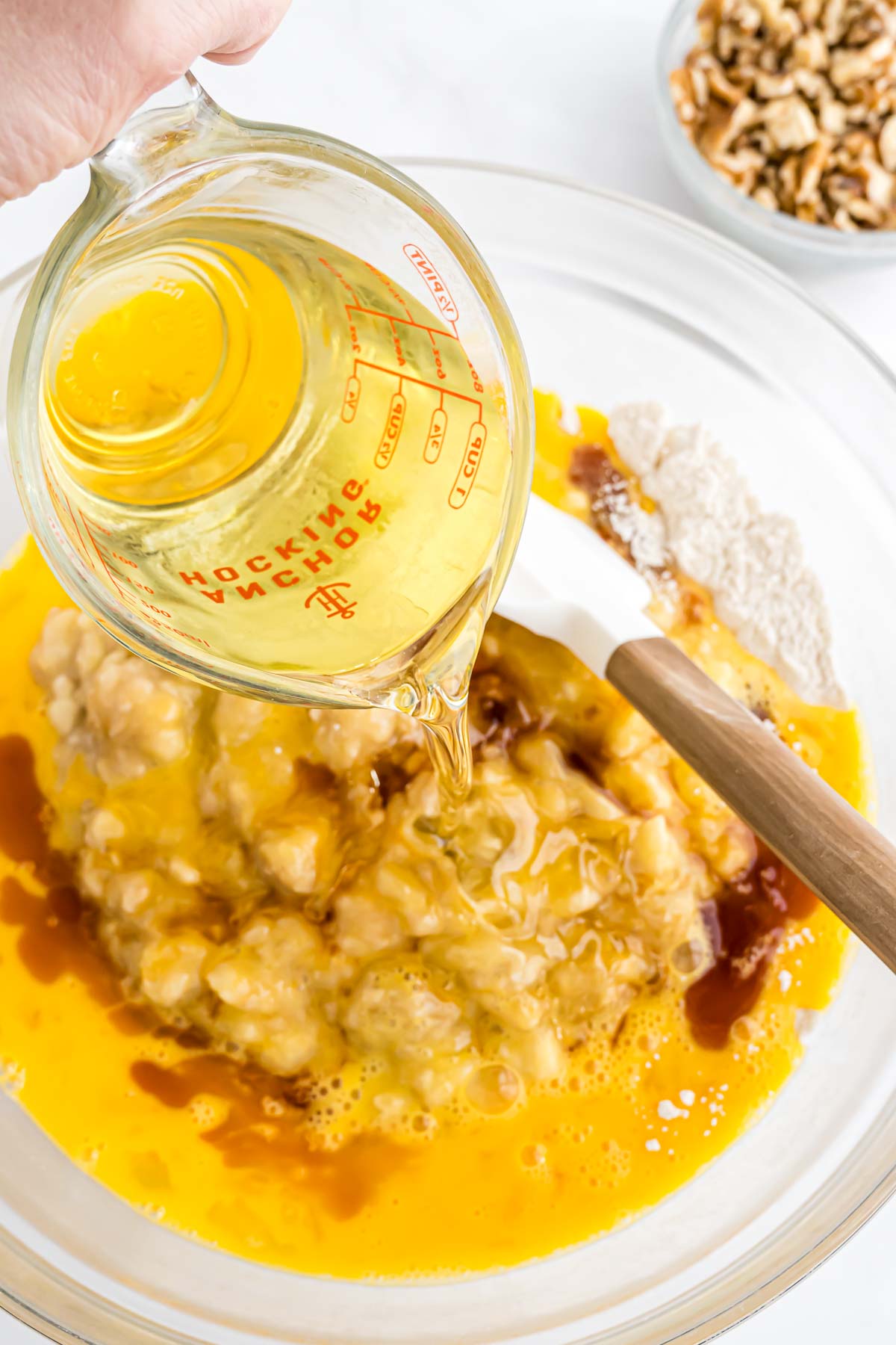 The wet ingredients for the banana nut bread being combined in a large mixing bowl.